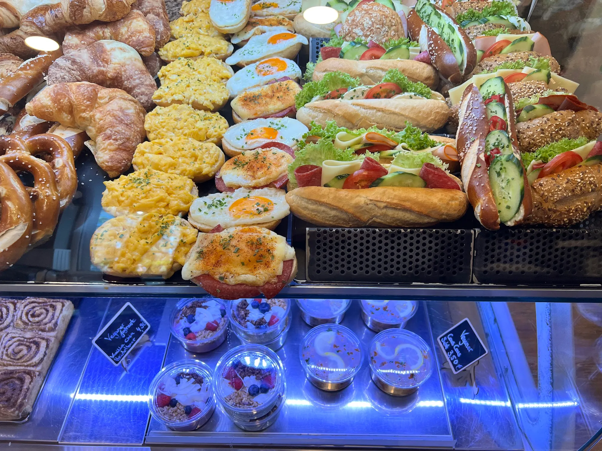 Die volle Theke: Croissants, Rührei-Brötchen, Spiegelei-Brötchen, belegte Baguettes, Brezeln und Joghurt-Bowls